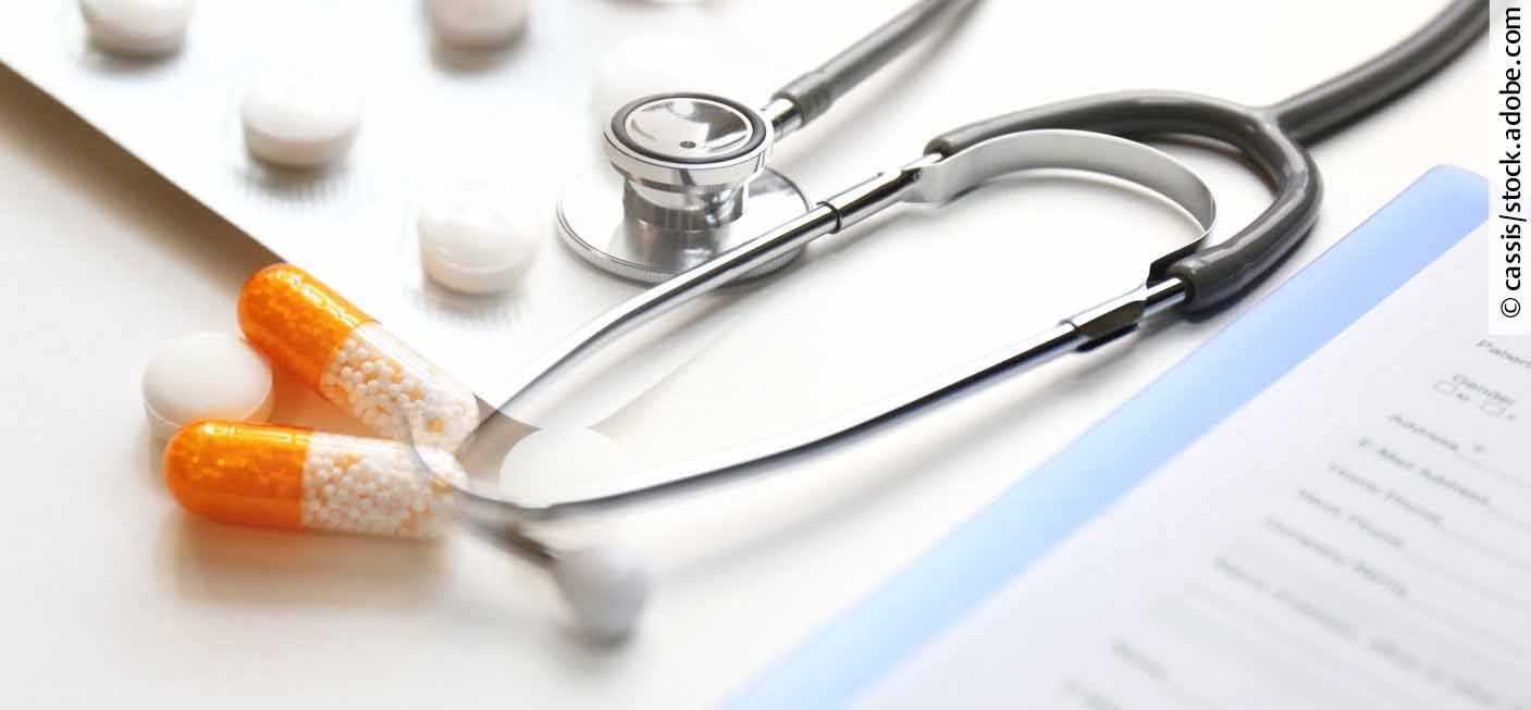 Stethoskop und Tabletten auf weißem Untergrund liegend